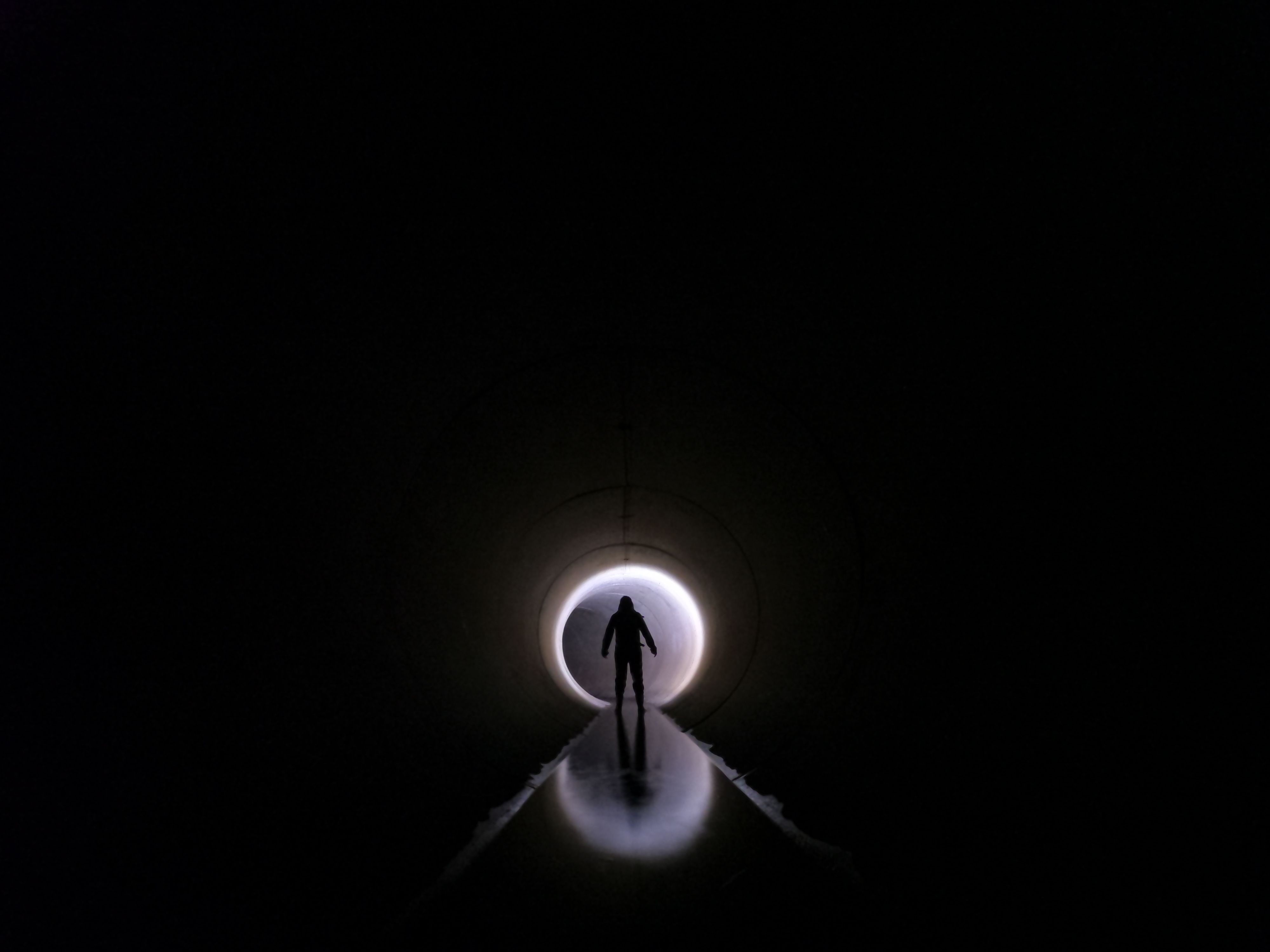 Dramatic silhouette of an individual standing in a dark tunnel with light at the