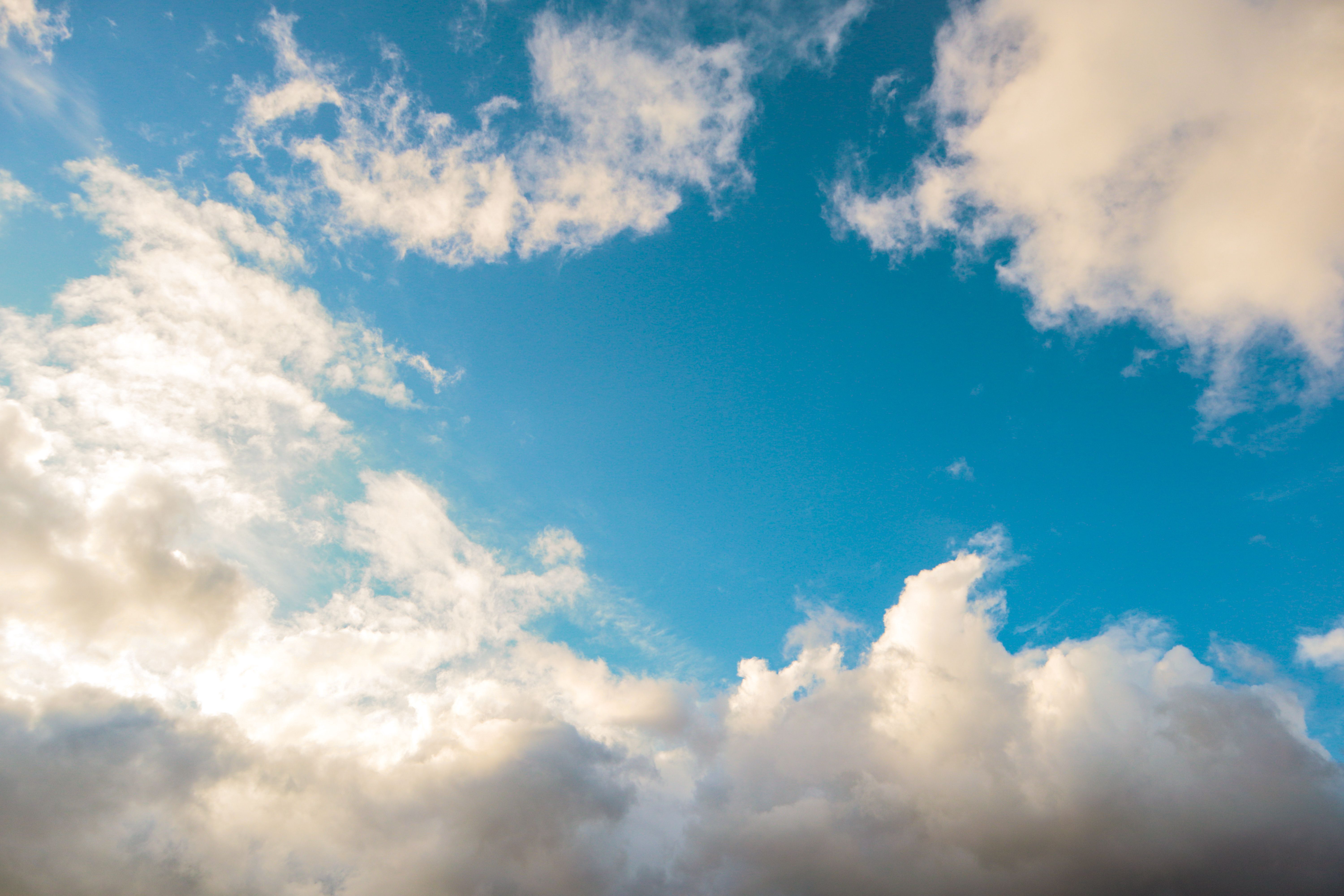 A bright blue sky adorned with fluffy white clouds, creating a peaceful and sere