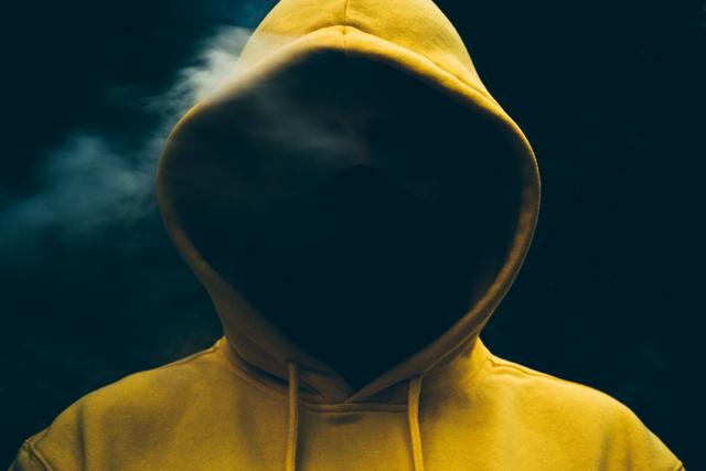 Mysterious hooded figure shrouded in smoke, creating an enigmatic silhouette.