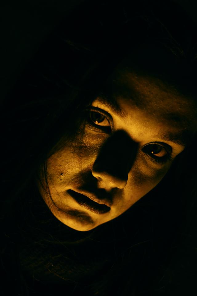Dark, haunting portrait featuring intense lighting on a person's face.