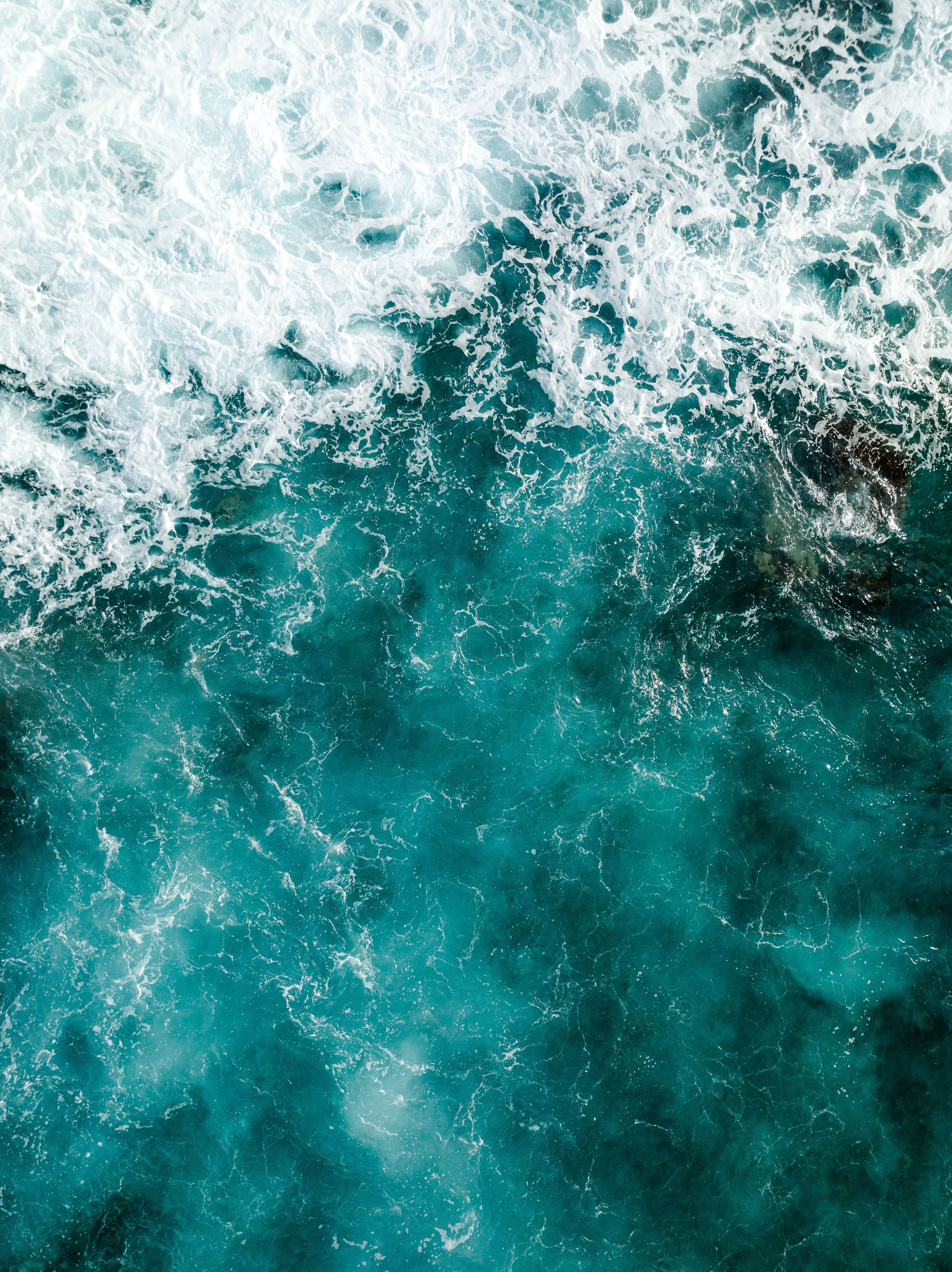 Breathtaking aerial shot of turquoise ocean waves crashing, showcasing nature's 