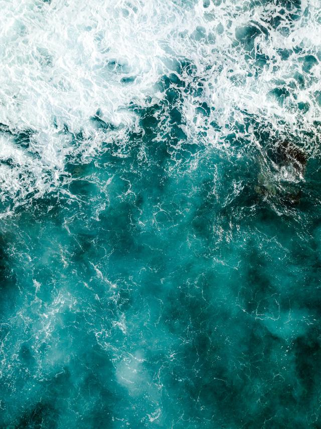 Breathtaking aerial shot of turquoise ocean waves crashing, showcasing nature's