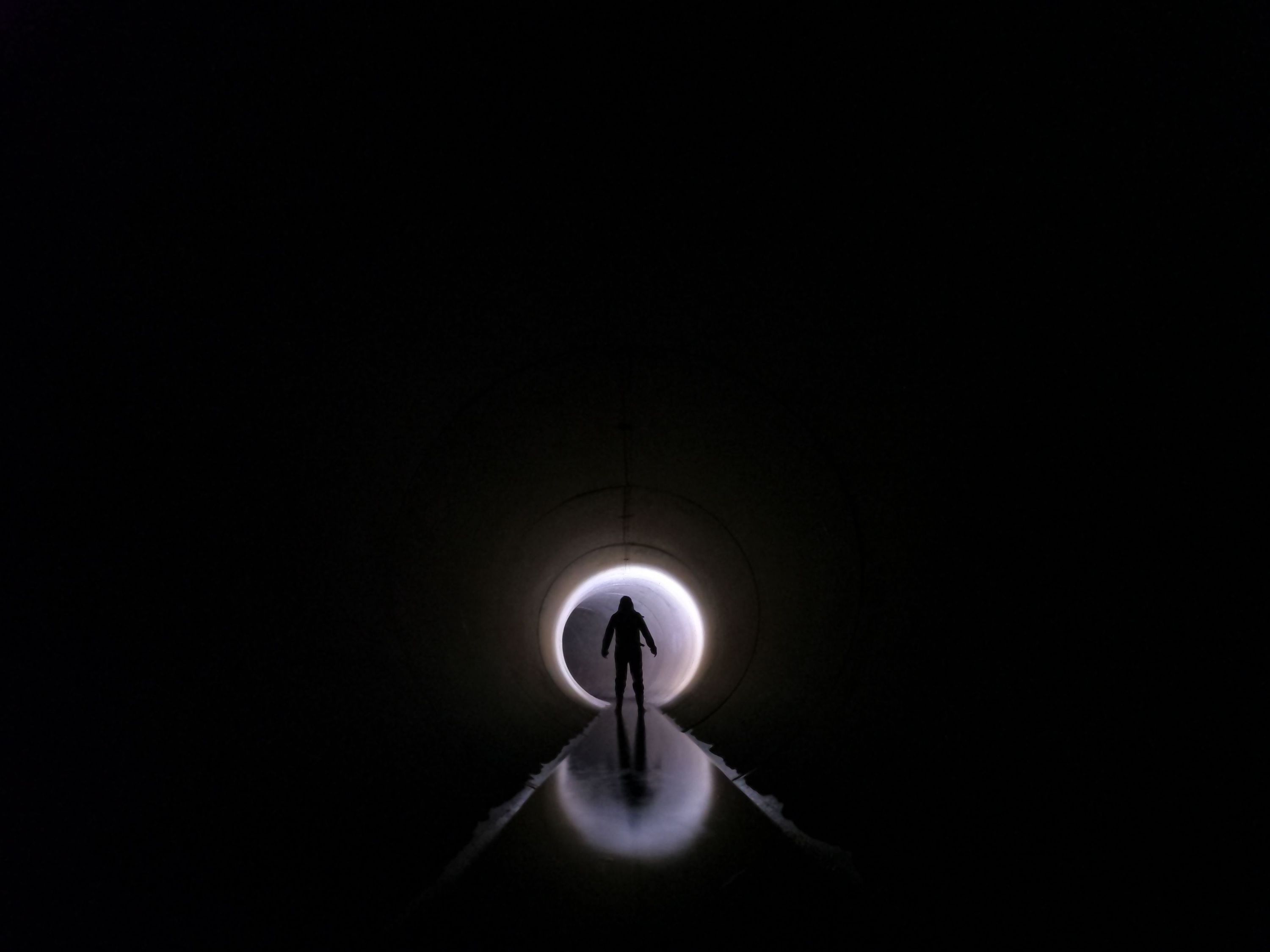 Dramatic silhouette of an individual standing in a dark tunnel with light at the