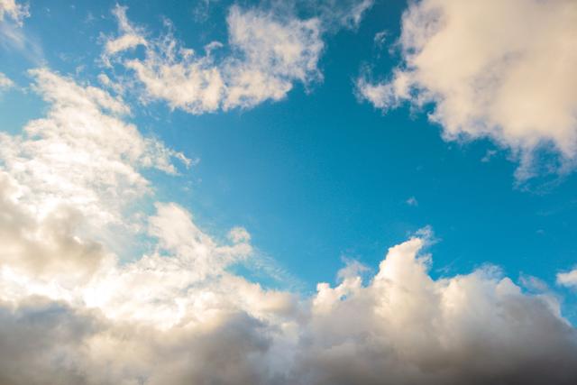 A bright blue sky adorned with fluffy white clouds, creating a peaceful and sere