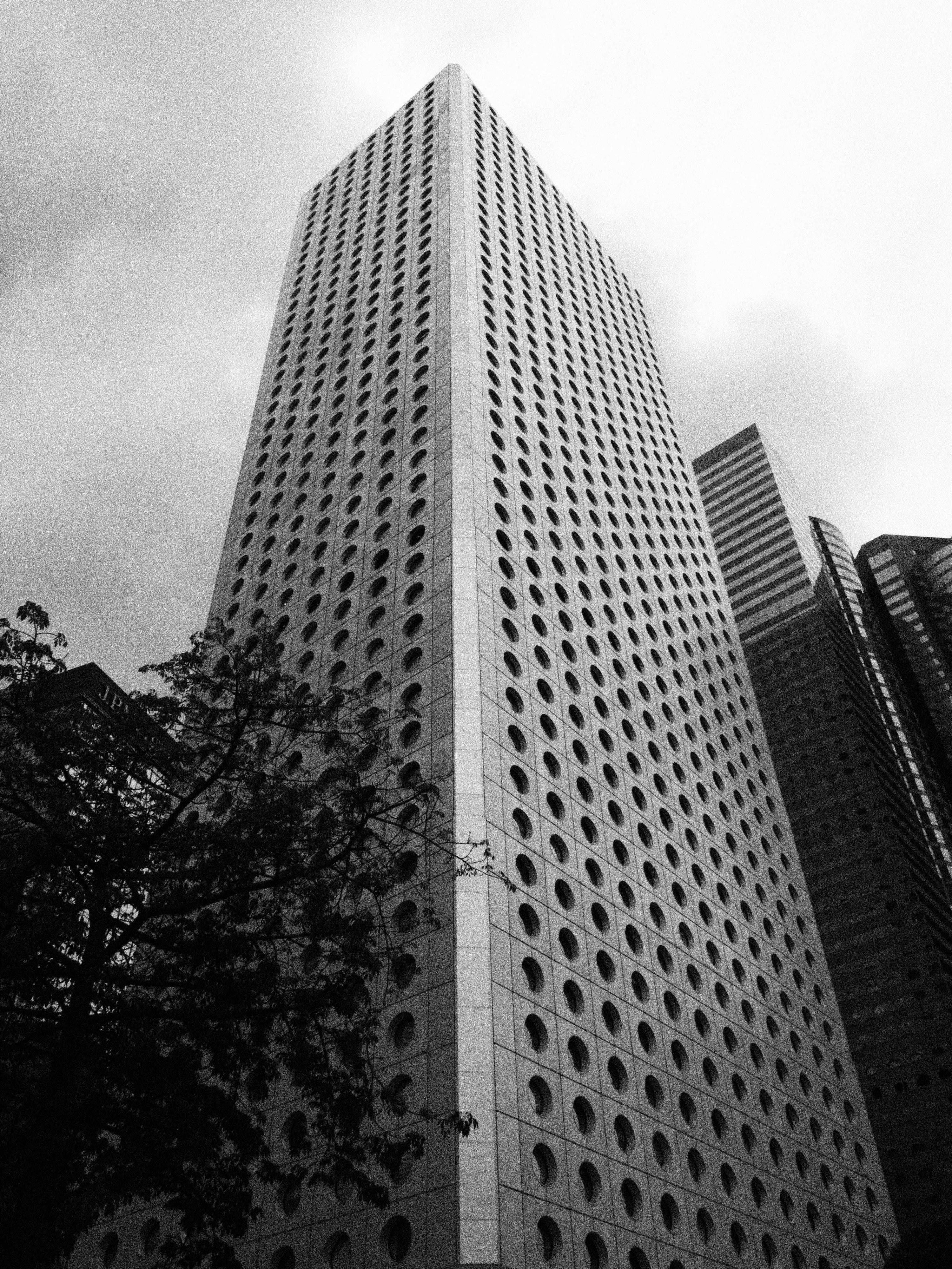 Striking black and white photo of a modern skyscraper with circular windows in a