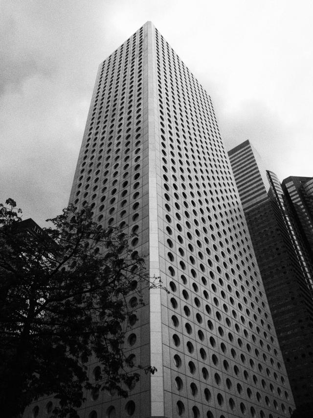 Striking black and white photo of a modern skyscraper with circular windows in a