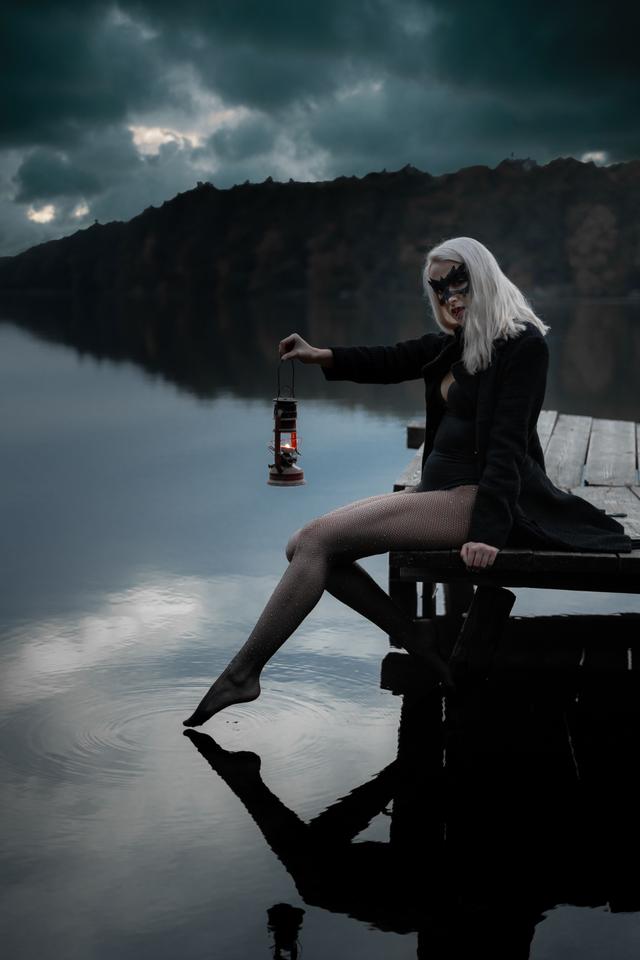 Side view of blond female in trendy apparel and decorative mask reflecting in ri